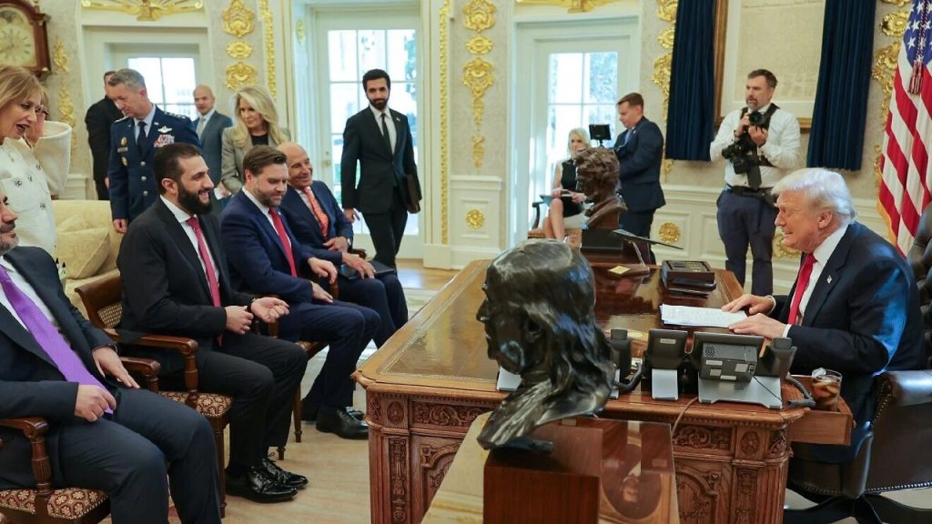 Donald Trump sitting at his desk in the Oval Office, speaking to a delegation of officials seated across from him