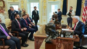 Donald Trump sitting at his desk in the Oval Office, speaking to a delegation of officials seated across from him