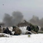 Ukrainian soldiers firing a heavy artillery cannon in a snowy field during the fourth year of the conflict.