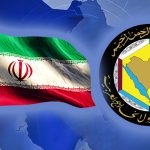 A digital composition featuring the waving national flag of Iran on the left and the official emblem of the Cooperation Council for the Arab States of the Gulf (GCC) on the right, set against a blue world map background.