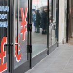 Exterior of a Russian currency exchange office with large dollar, pound, and yen symbols on the glass door.