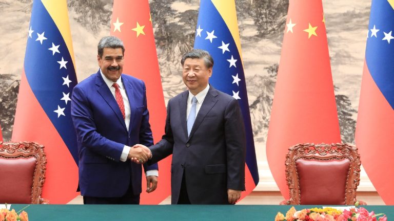 Chinese President Xi Jinping and Venezuelan President Nicolás Maduro shaking hands in front of several Chinese and Venezuelan flags