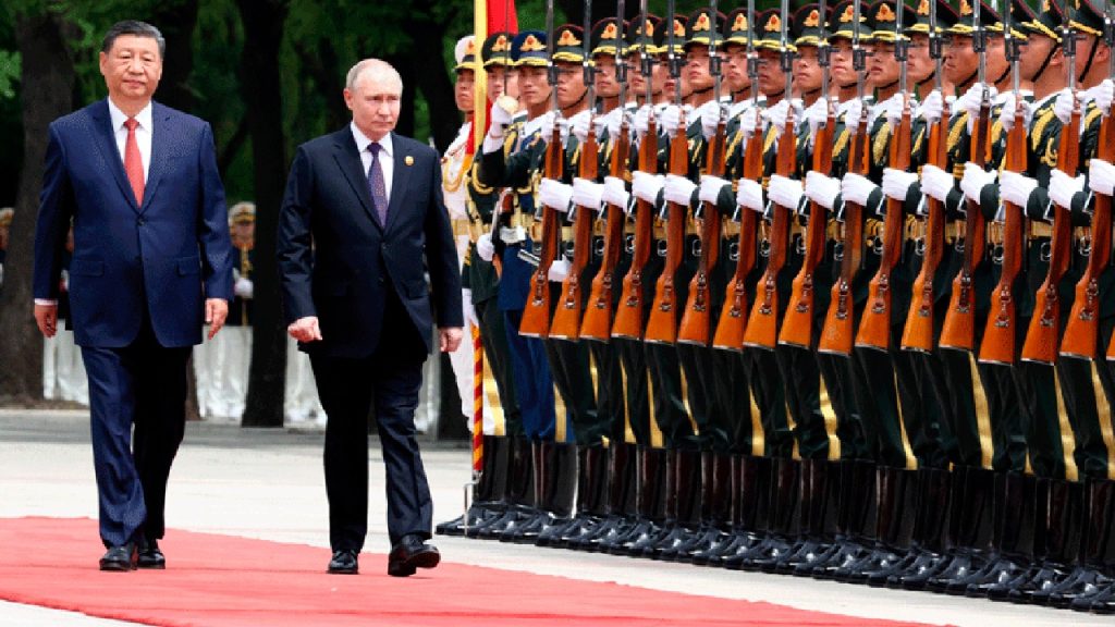 Xi Jinping and Vladimir Putin walking side-by-side past a long line of Chinese soldiers standing at attention with rifles.