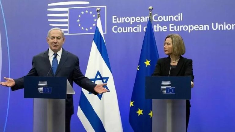 Benjamin Netanyahu and Federica Mogherini standing behind blue podiums with the European Council logo during a press conference, with Israeli and EU flags in the middle.