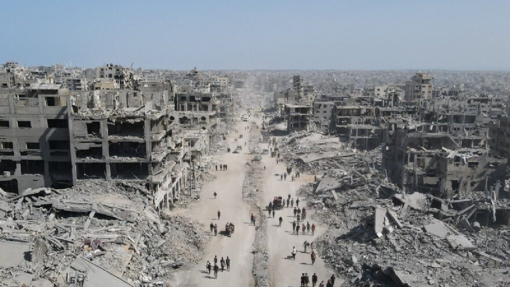Aerial view of a completely devastated urban area with destroyed buildings and rubble-filled streets.