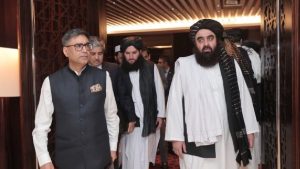 Indian diplomat in a vest walking with a delegation of Taliban officials wearing turbans and traditional Afghan attire