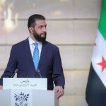 A wide view of a city in Syria, showing areas of destruction contrasted with signs of tentative rebuilding after the fall of Bashar al-Assad