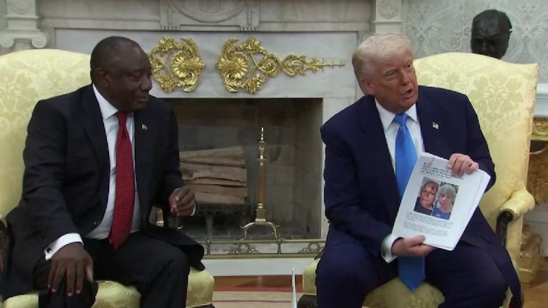 Donald Trump and Cyril Ramaphosa seated indoors, with Trump holding a document showing a couple's photo