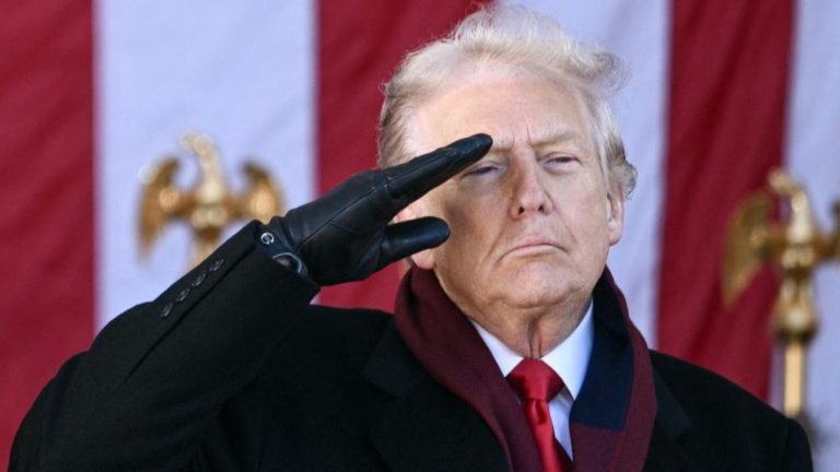 Donald Trump wearing a black overcoat, leather gloves, and a red scarf, delivering a military salute outdoors