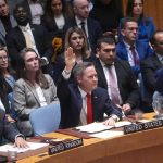 A group of diplomats and delegates, including the U.S. representative, raising their hands to vote at a United Nations Security Council session