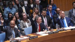 A group of diplomats and delegates, including the U.S. representative, raising their hands to vote at a United Nations Security Council session