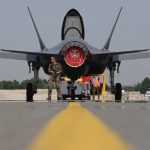 A U.S. F-35 Lightning II stealth fighter jet flying in the sky, with the Turkish flag blurred in the foreground