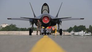 A U.S. F-35 Lightning II stealth fighter jet flying in the sky, with the Turkish flag blurred in the foreground