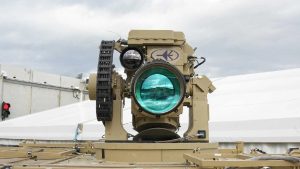 A sophisticated tan-colored laser or optical weapon system mounted on a platform.