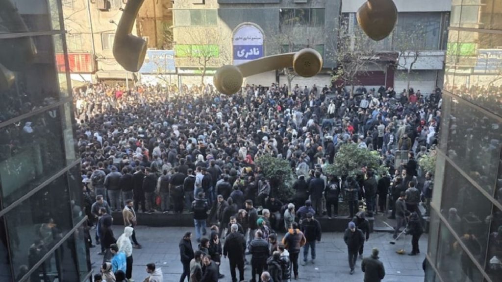 A high-angle view of a large crowd of people gathered in a public square or courtyard between buildings.