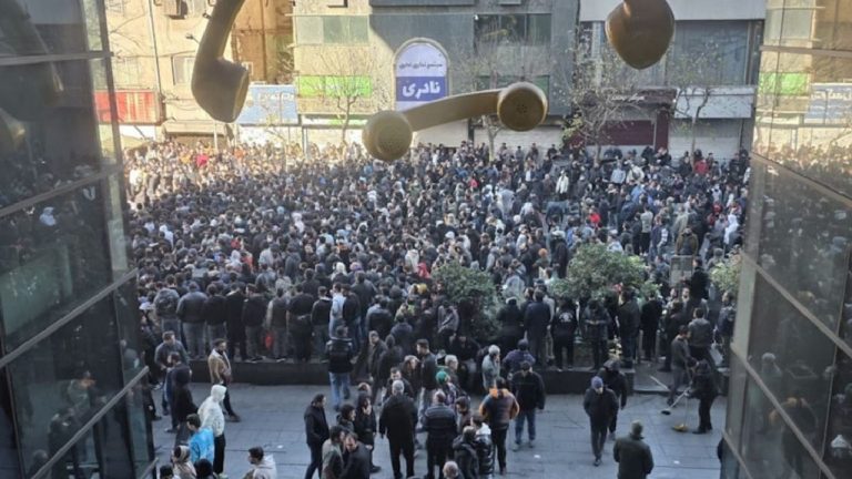 A high-angle view of a large crowd of people gathered in a public square or courtyard between buildings.