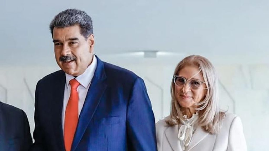 Nicolás Maduro in a blue suit and a woman with grey hair and glasses standing next to each other.