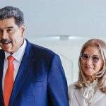 Nicolás Maduro in a blue suit and a woman with grey hair and glasses standing next to each other.