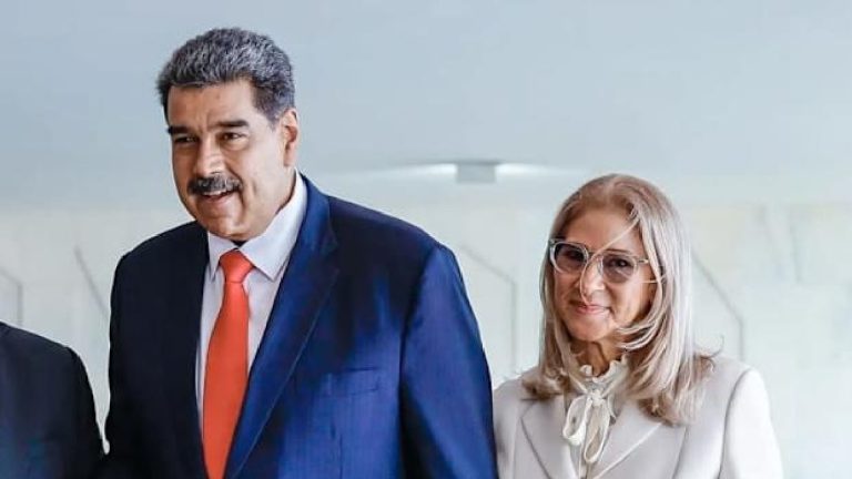 Nicolás Maduro in a blue suit and a woman with grey hair and glasses standing next to each other.