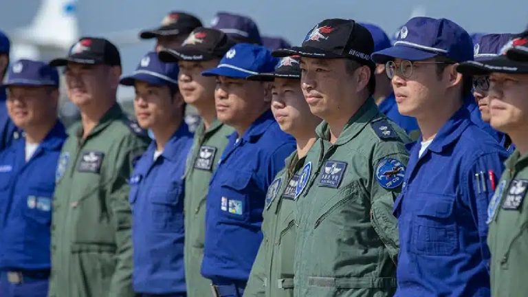 A group of military personnel in blue and green flight suits standing in formation.