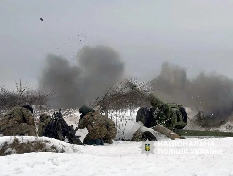 Ukrainian soldiers firing a heavy artillery cannon in a snowy field during the fourth year of the conflict.