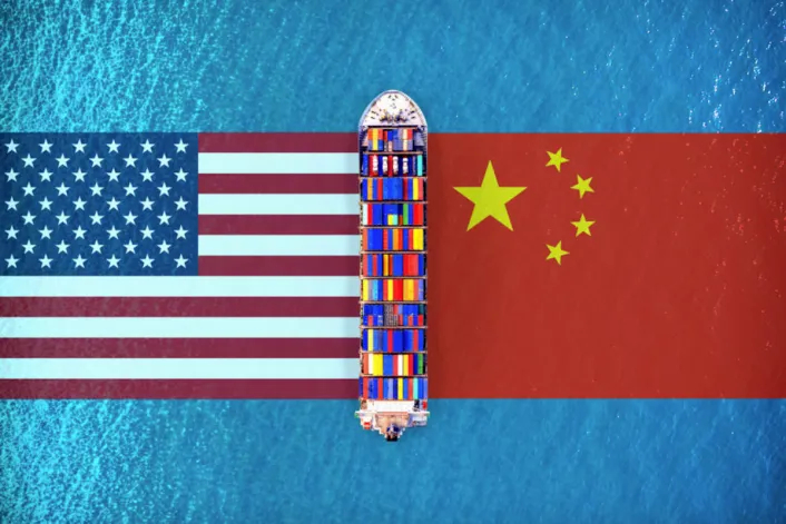 Container ship crossing between the US and Chinese flags representing global trade tensions.