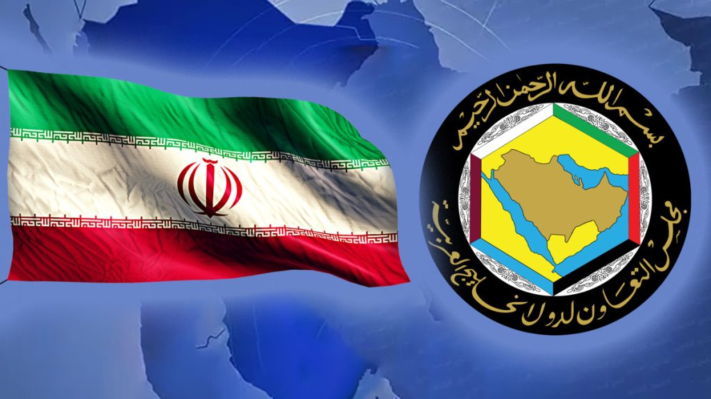 A digital composition featuring the waving national flag of Iran on the left and the official emblem of the Cooperation Council for the Arab States of the Gulf (GCC) on the right, set against a blue world map background.