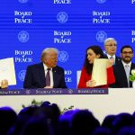 A group of men and one woman sit behind a long white table labeled "BOARD of PEACE" while two men hold up open folders showing documents.