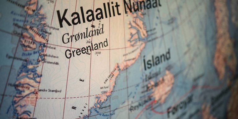 A close-up, shallow depth-of-field photograph of a geographical globe focusing on Greenland (Kalaallit Nunaat) and Iceland.