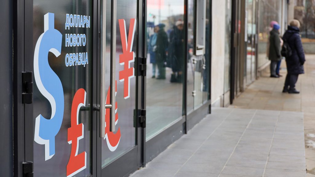 Exterior of a Russian currency exchange office with large dollar, pound, and yen symbols on the glass door.