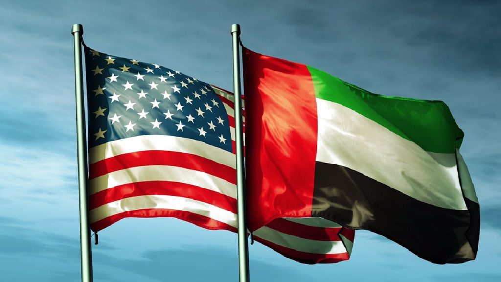 The national flags of the United States of America and the United Arab Emirates flying side-by-side against a blue sky with soft clouds.