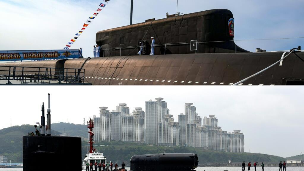A split-screen image showing a large Russian nuclear submarine with sailors on deck in the top half, and a harbor scene with a smaller black submarine and tall coastal residential buildings in the bottom half.