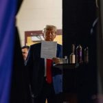 Candid behind-the-scenes shot of Donald Trump reading a document backstage.