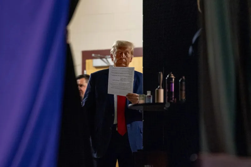 Candid behind-the-scenes shot of Donald Trump reading a document backstage.
