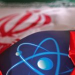 A close-up shot of a blue surface with a white atomic symbol, partially covered by a red and white flag.
