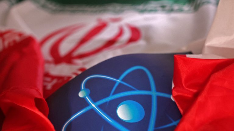 A close-up shot of a blue surface with a white atomic symbol, partially covered by a red and white flag.