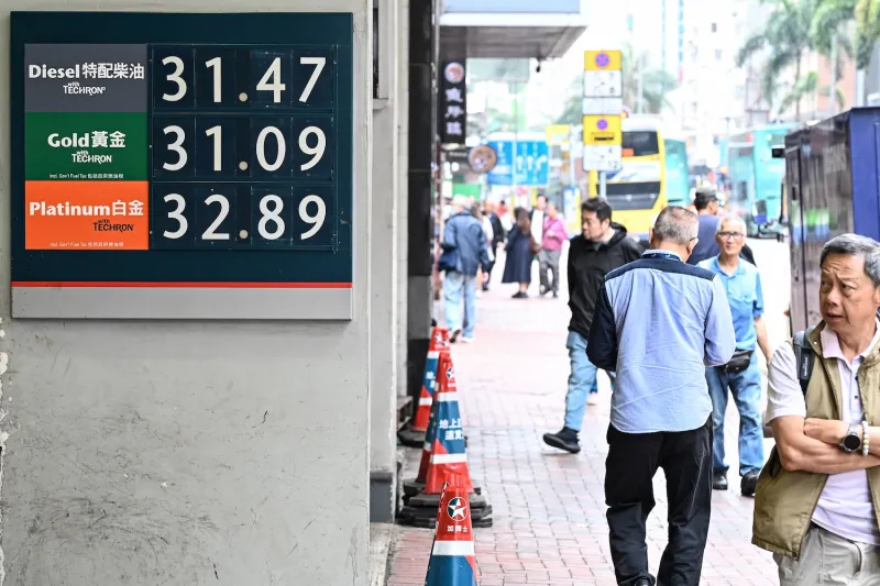 Digital gas price display board in Hong Kong showing Diesel, Gold, and Platinum fuel rates with pedestrians.