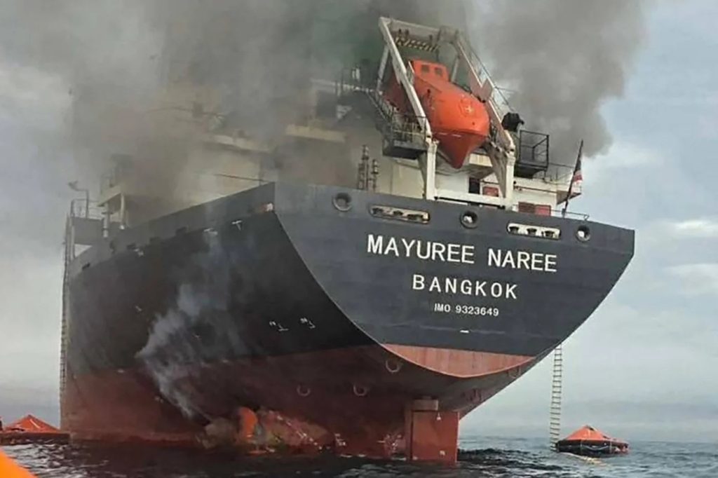 A large cargo ship named "MAYUREE NAREE" with smoke billowing from its stern while at sea.