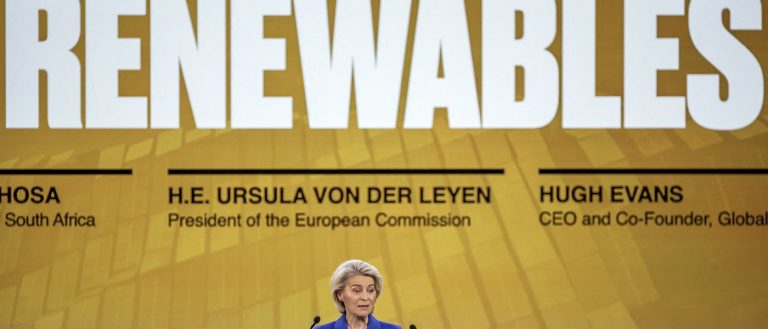 Ursula von der Leyen speaking at a podium with a large "RENEWABLES" sign in the background.