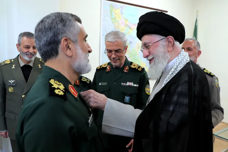 Ali Khamenei pinning a medal onto the chest of Amir Ali Hajizadeh's military uniform, while Mohammad Bagheri and Abdolrahim Mousavi watch from the background.