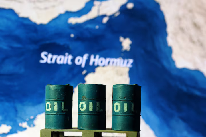 Three miniature green oil barrels placed in front of a map focusing on the Strait of Hormuz.