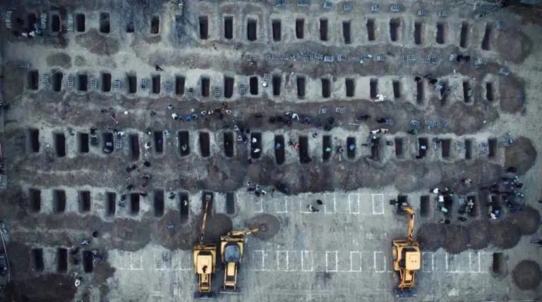 A high-angle aerial view of a large burial site showing numerous rows of open rectangular graves in the earth that belongs to 180 girl students were killed in minab school by us missiles.