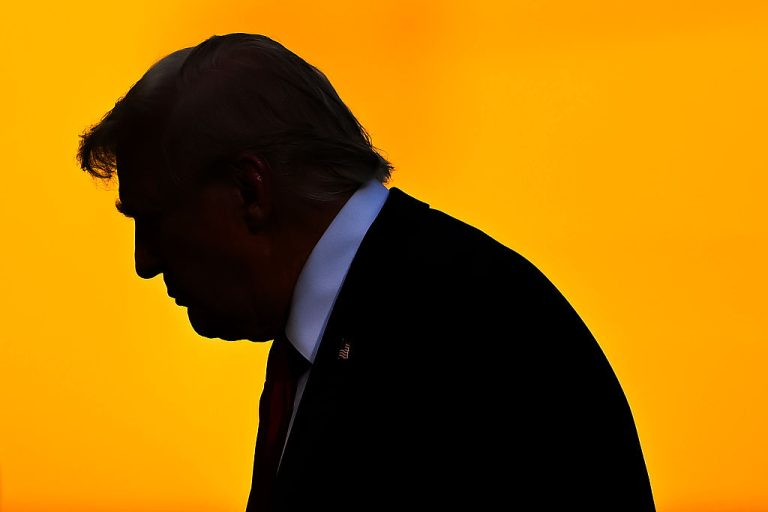 Silhouette of Donald Trump in profile against a solid bright orange background.