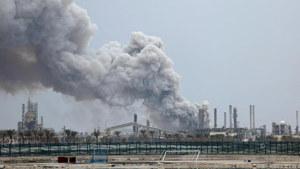 Thick smoke billowing from an industrial oil refinery facility after an attack or explosion.