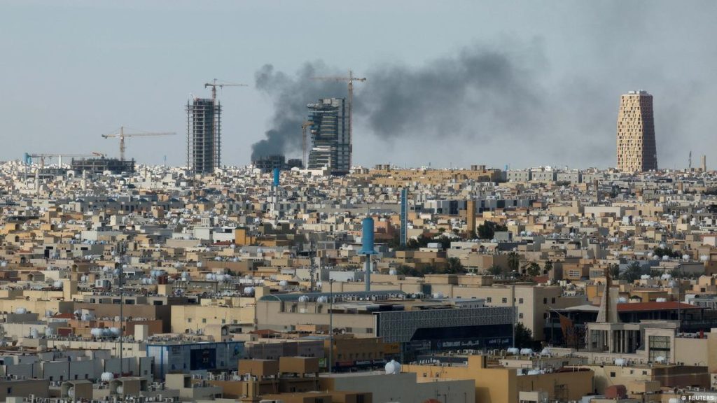 Panoramic view of a Middle Eastern city skyline with smoke rising from buildings under construction.