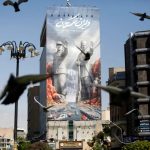 A large mural on a building in Tehran featuring historical figures and naval ships, with birds flying in the foreground.