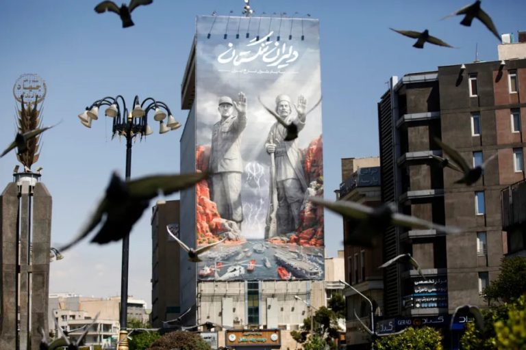 A large mural on a building in Tehran featuring historical figures and naval ships, with birds flying in the foreground.