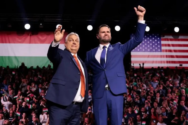 Viktor Orbán and JD Vance standing together on stage during a political event with Hungarian and US flags.
