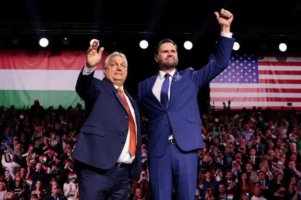 Viktor Orbán and JD Vance standing together on stage during a political event with Hungarian and US flags.