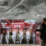 A large outdoor banner in Iran featuring various historical figures and the text "Murdered By USA" in English and Persian.